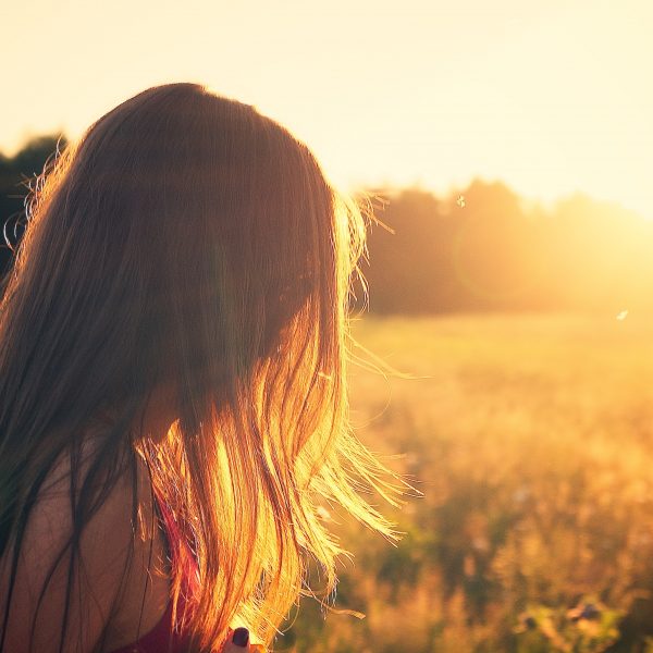 girl staring into a sunset in a field