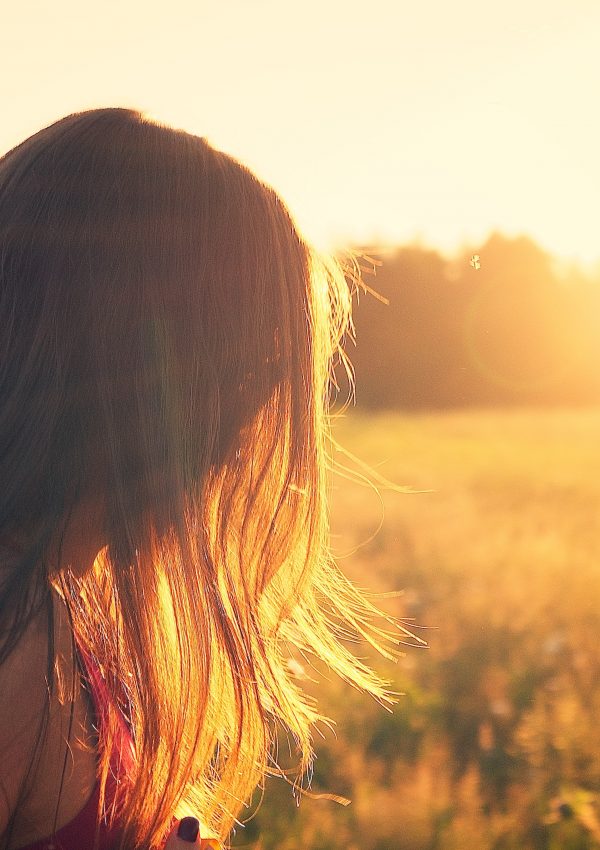 girl staring into a sunset in a field