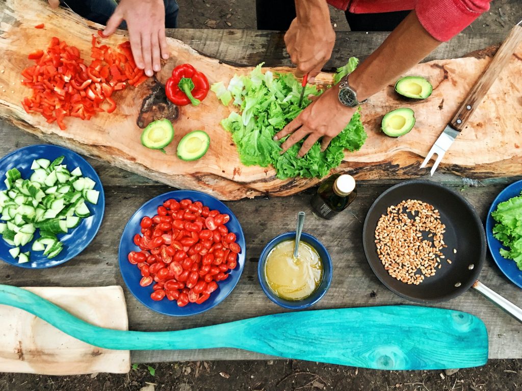 Colourful foods on a table, hands at work for meal prep