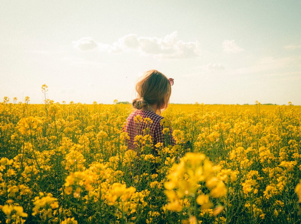 Girl wearing plaid shirt in field of yellow flowers