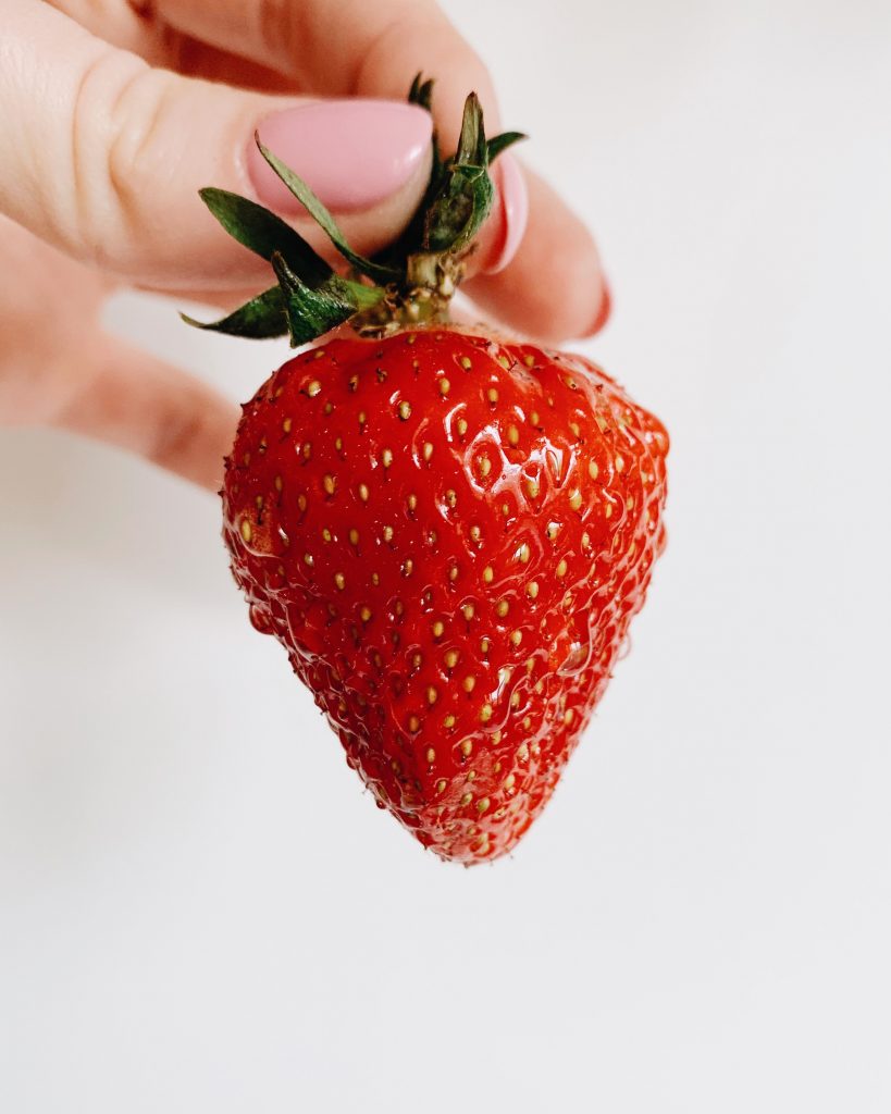 Hand holding a fresh strawberry