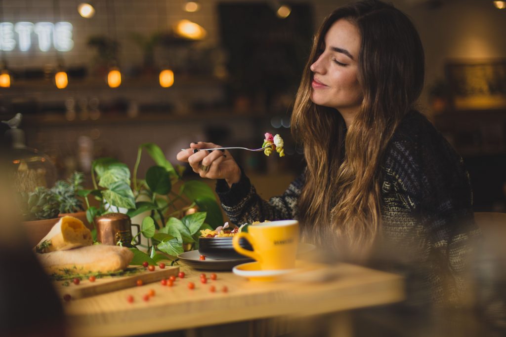 Girl smiling while she eats peacefully at a table with bread and coffee