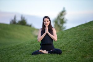 For gut health - woman sitting in green field meditating and doing yoga