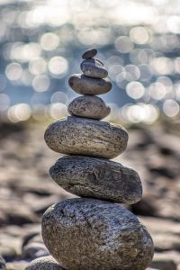 Rocks and pebbles that are stacked and balancing on top of each other at a beach on a sunny day