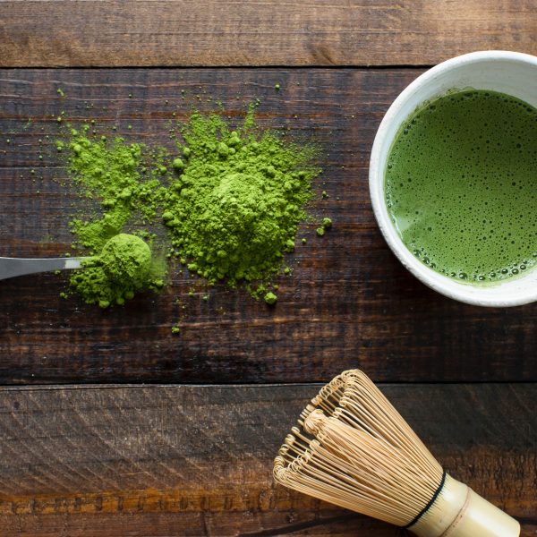 Matcha powder on a wooden table and in a cup