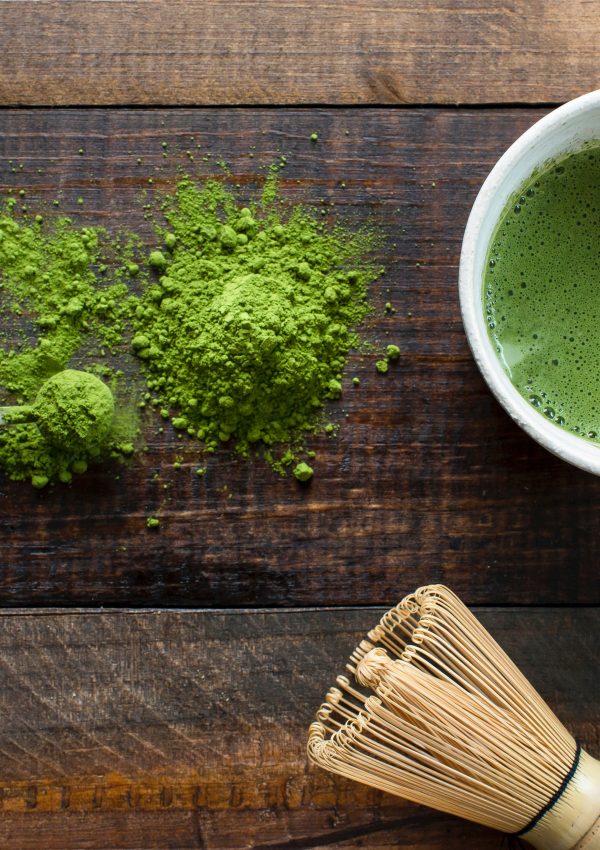 Matcha powder on a wooden table and in a cup