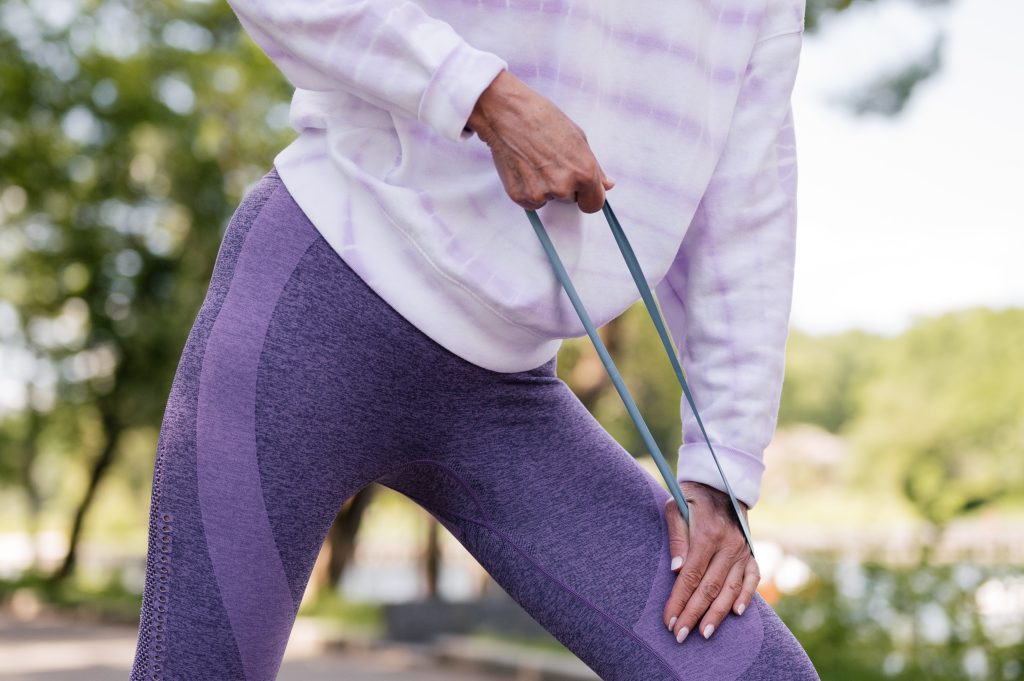 Woman in purple yoga outfit using a resistance band to exercise