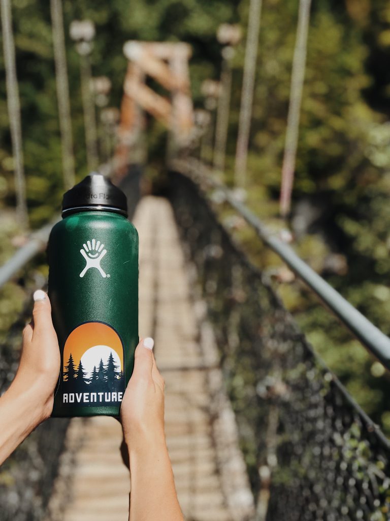 Woman holding a water bottle on a bridge in the forest