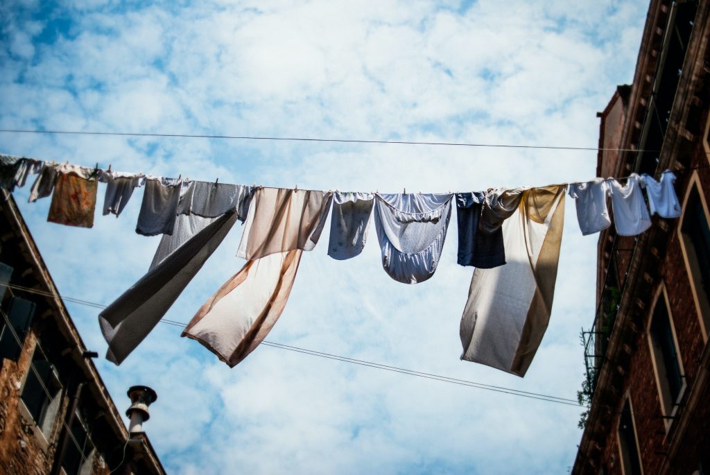 Clothes hanging on a line between buildings, with the blue sky in the background.