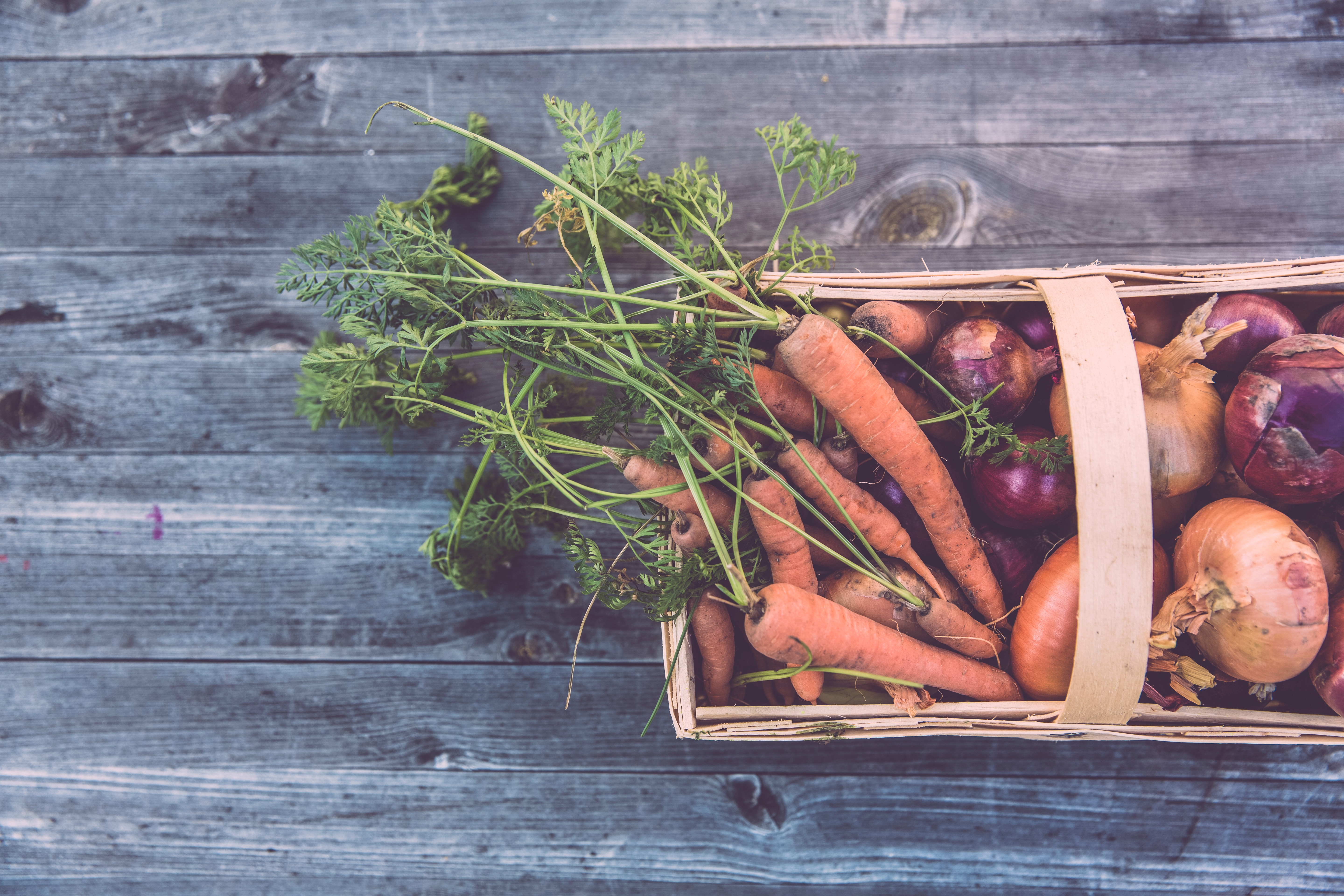 wooden basket filled with vegetables on a blue-gray wooden background