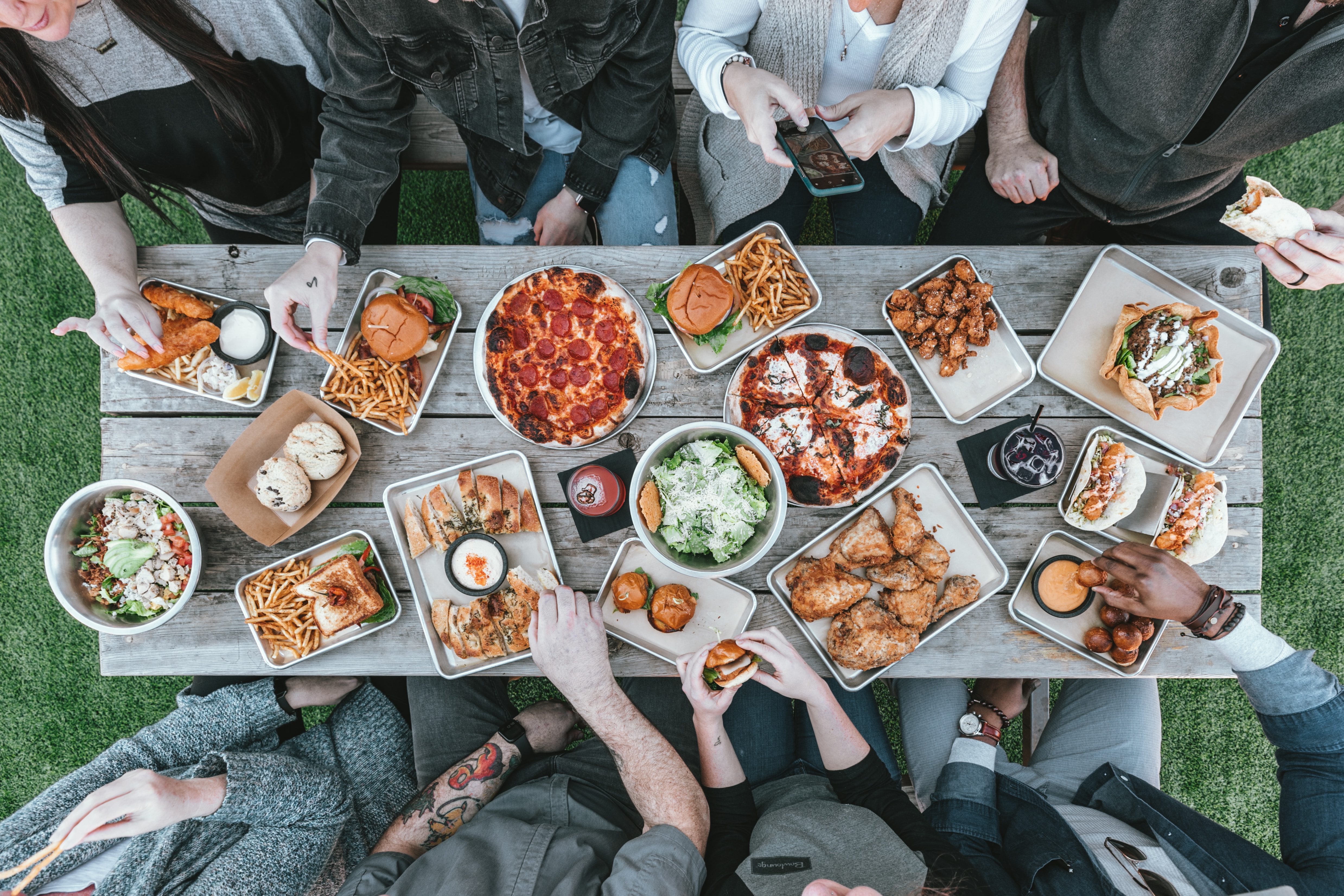 gray dinner table with plates of food and people sitting around the table, view from above